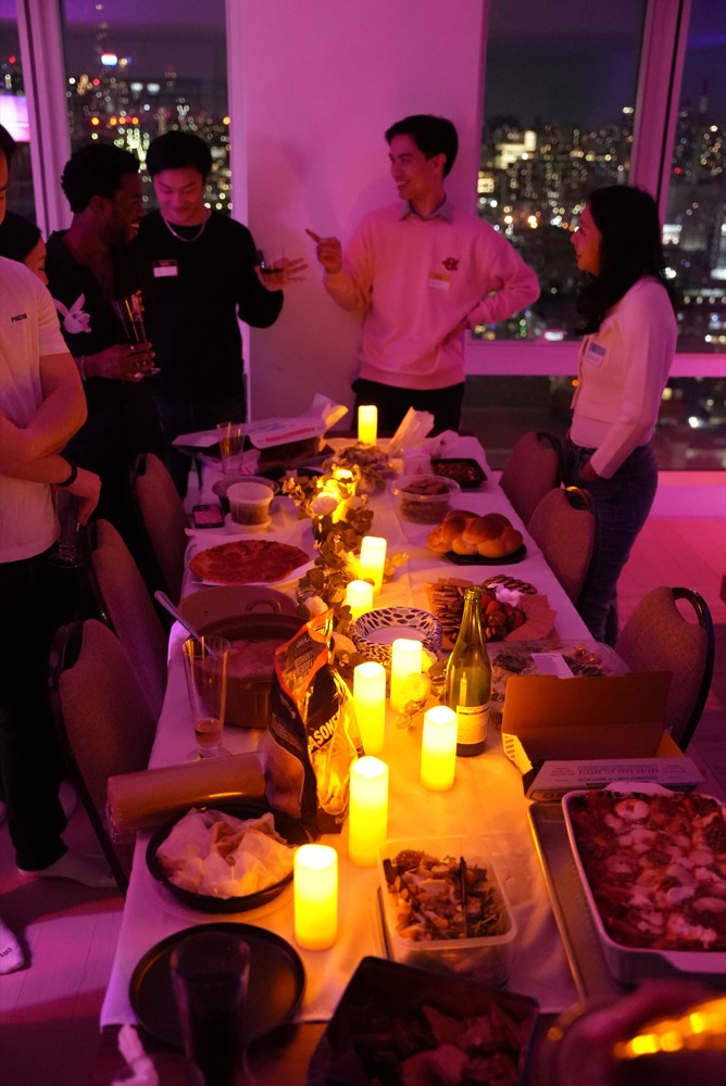 friends chatting over a candlelit potluck with skyline views