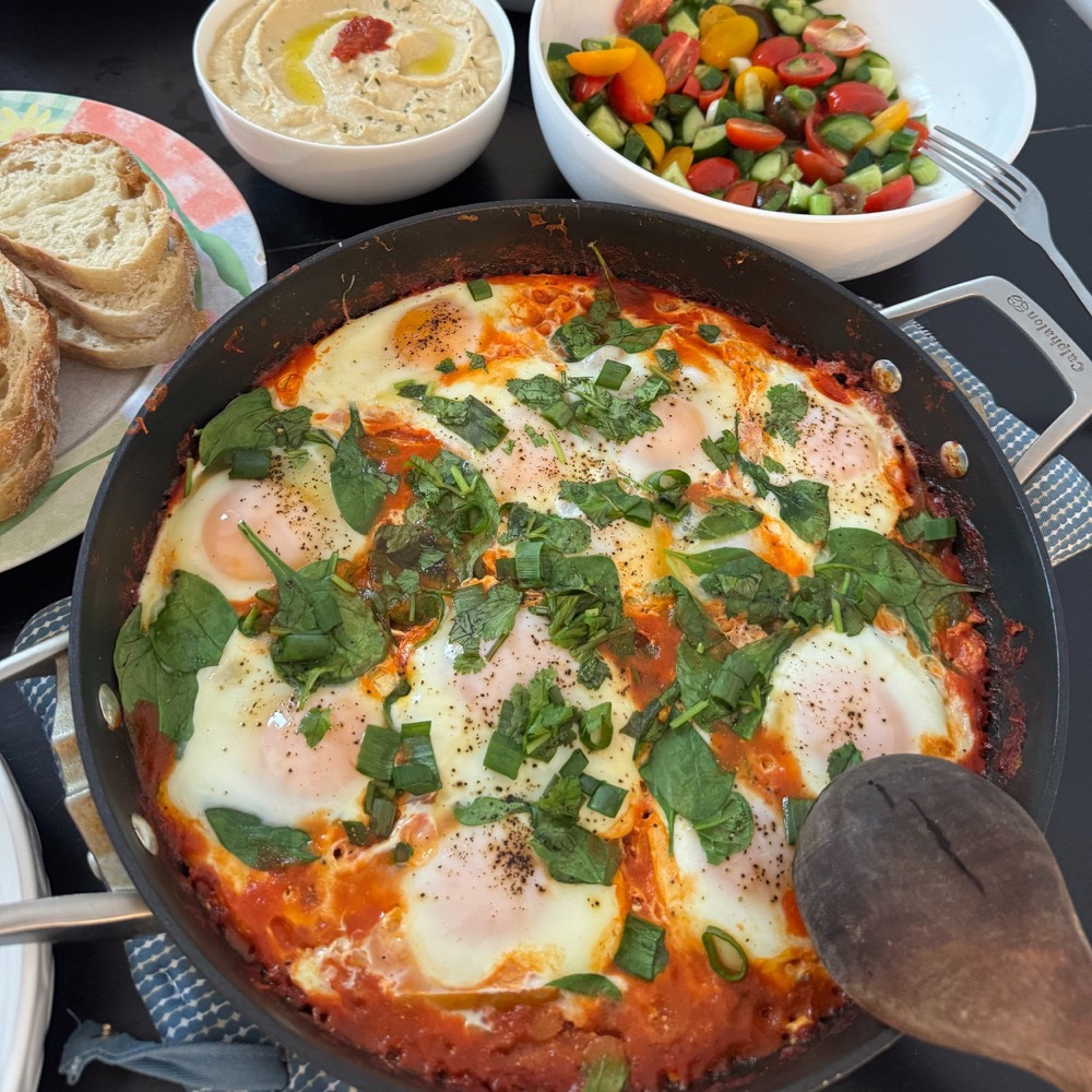 shakshuka skillet with hummus, salad, and bread