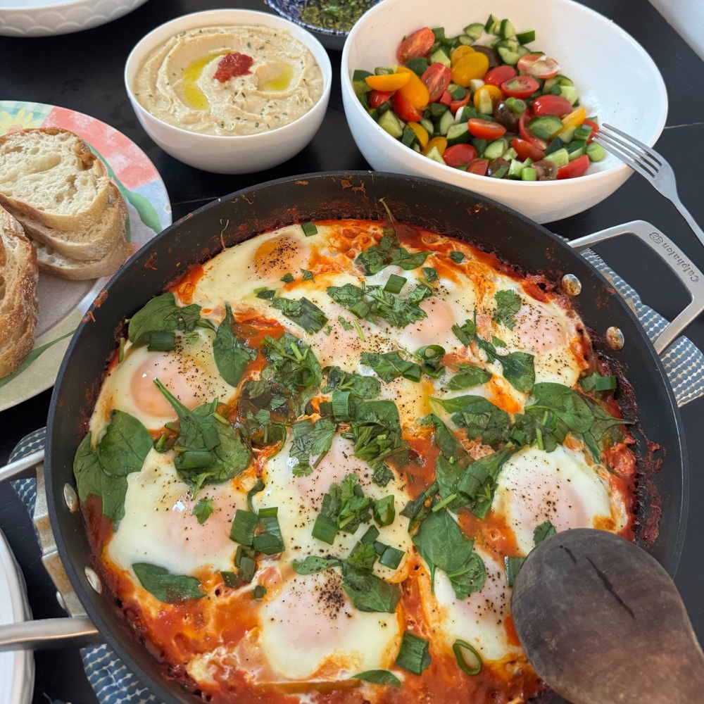 shakshuka skillet with hummus, salad, and bread
