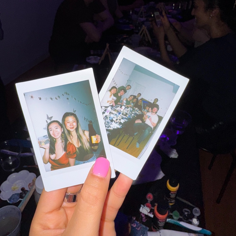 hand holding two instant photos from a paint night