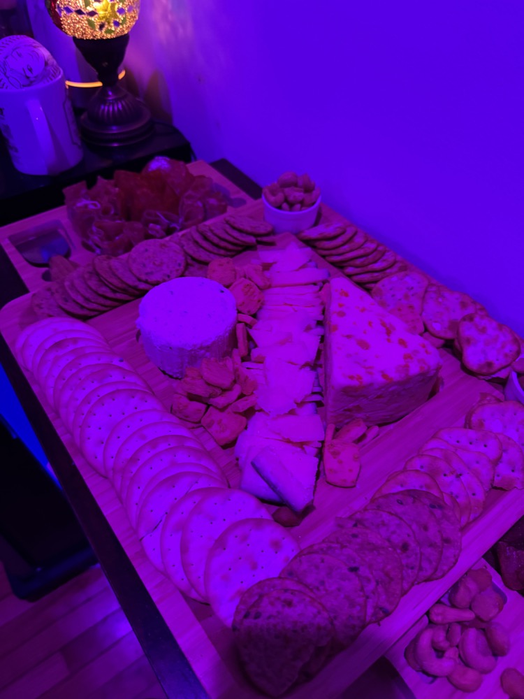 cheese and cracker board under purple party lighting