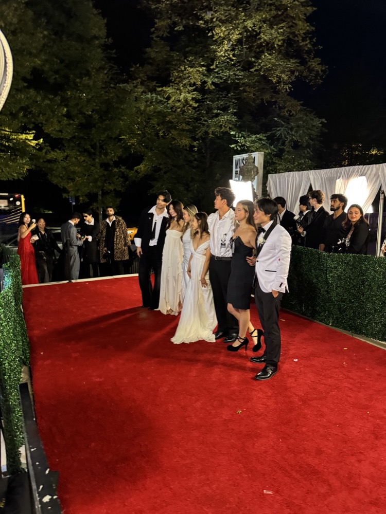 group in formalwear posing on a red carpet at night
