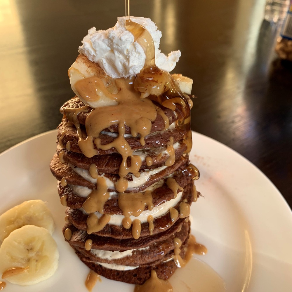 pancake stack with whipped cream, banana, and peanut butter