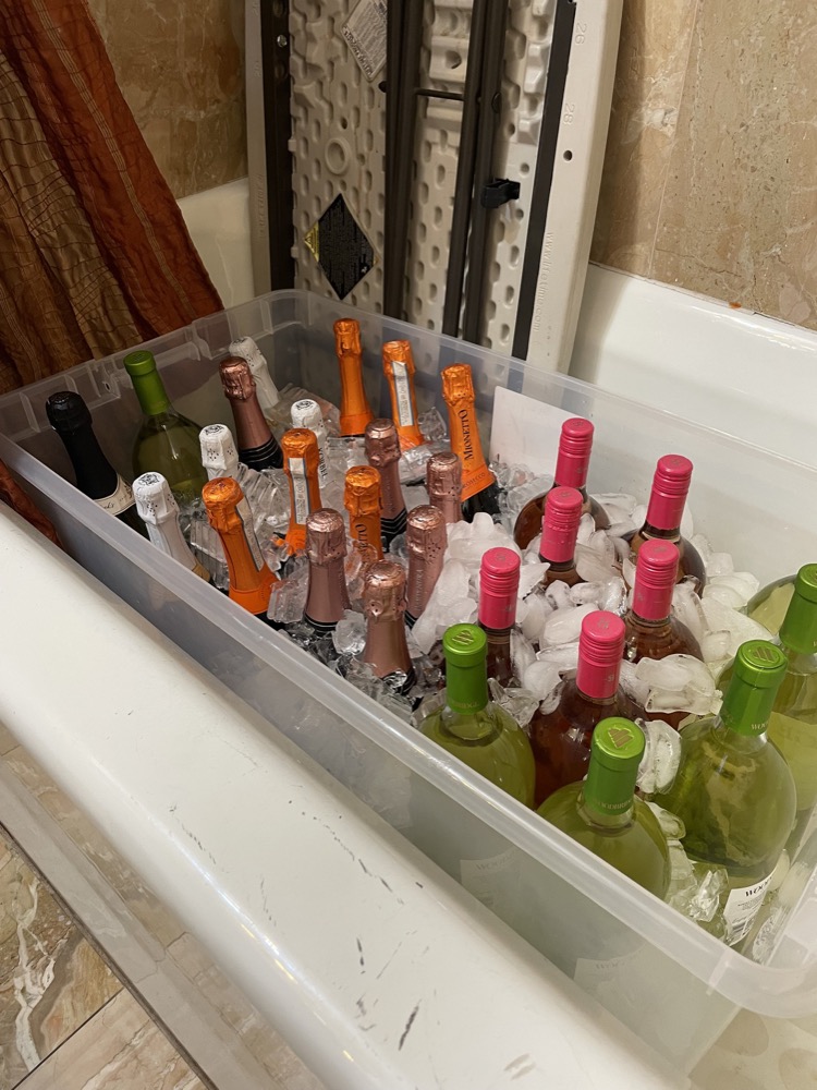 wine and prosecco bottles on ice in a bathtub